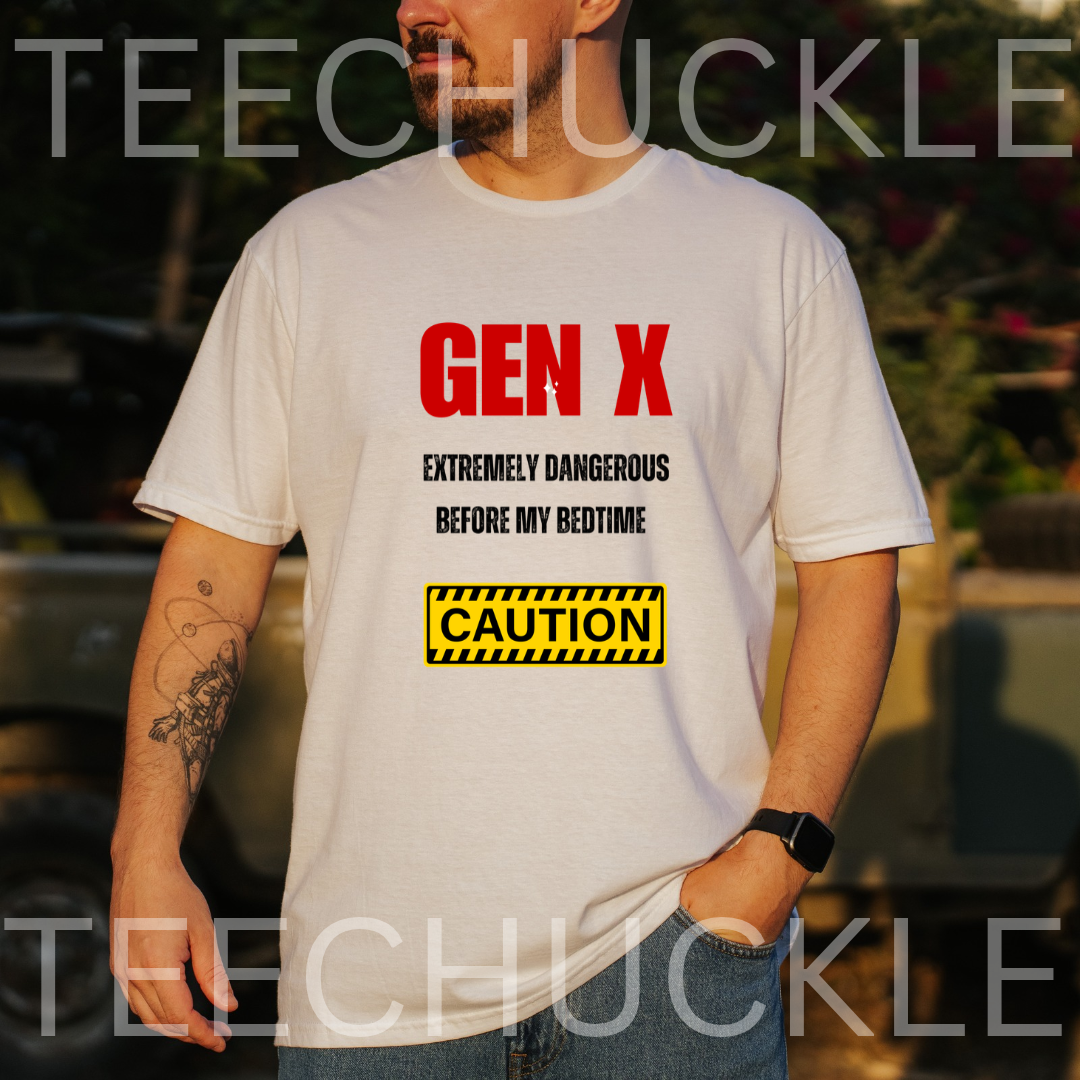 A man wearing a white graphic t-shirt with red and black text reading 'GEN X EXTREMELY DANGEROUS BEFORE MY BEDTIME' and a yellow caution-style box. The photo is taken outdoors with a blurred background