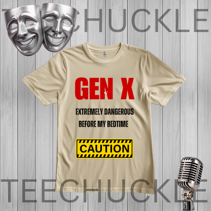 A sand graphic t-shirt displayed on a gray wood-plank background, featuring the text 'GEN X EXTREMELY DANGEROUS BEFORE MY BEDTIME' in red and black, and a yellow 'CAUTION' sign. Silver theater masks and a vintage microphone are shown as decorative props\