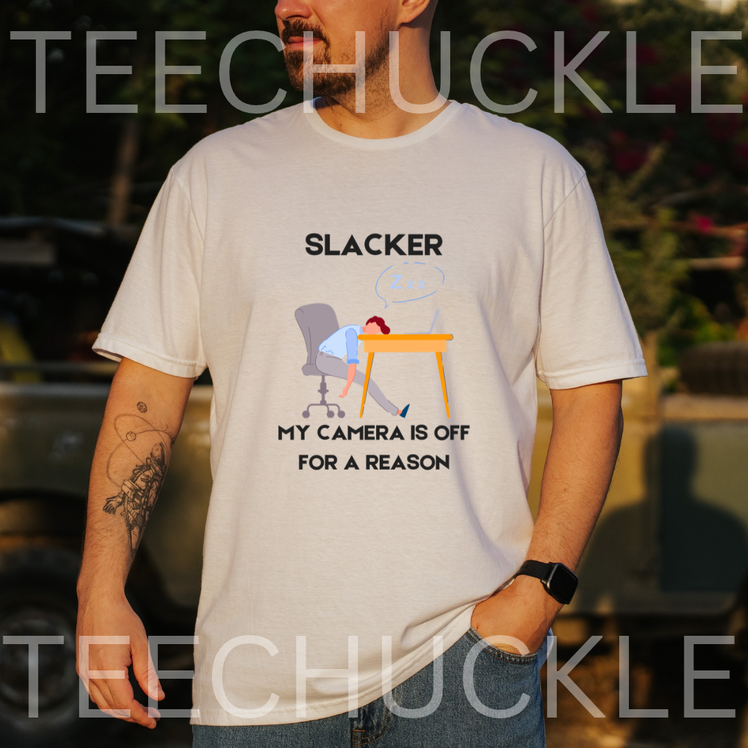 A white graphic t-shirt  featuring a cartoon illustration of a person sleeping at a desk with the text 'SLACKER, MY CAMERA IS OFF FOR A REASON'.