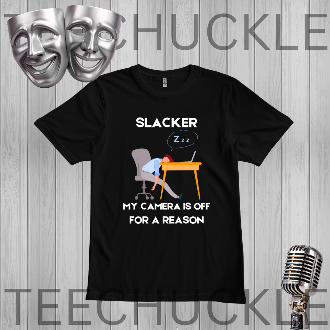 A black graphic t-shirt displayed on a gray wood plank background, featuring a cartoon illustration of a person sleeping at a desk with the text 'SLACKER, MY CAMERA IS OFF FOR A REASON'. The image includes decorative props like silver theater masks and a vintage microphone, 