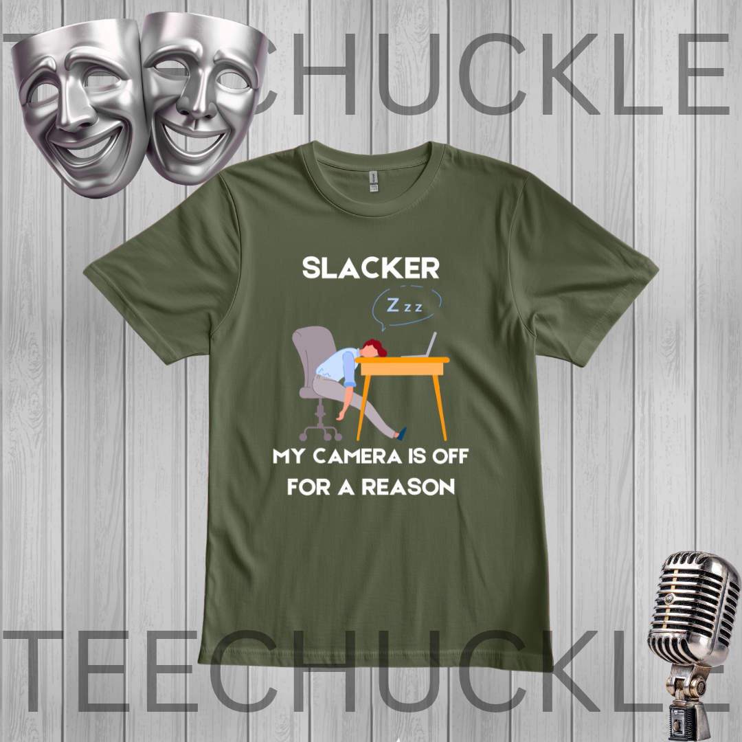 A green graphic t-shirt featuring a sleeping office worker at a desk with the text 'EXHAUSTED I'M NOT SLACKING I'M JUST CHARGING'. The t-shirt is displayed on a gray wood-plank background with a silver microphone, comedy masks