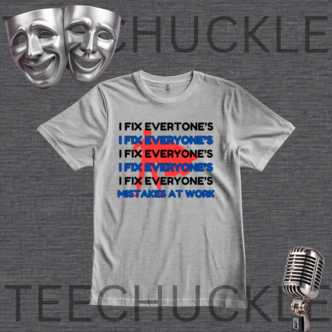 A gray graphic t-shirt featuring the text 'I FIX EVERYONE'S IX EVERYONE'S I FIX EVERYONE'S I FIX EVERYONE'S MISTAKES AT WORK' in black and blue, with a red 'X' crossing out the repeated phrase. The shirt is displayed on a dark gray textured background with silver comedy masks in the top-left corner and a vintage microphone in the bottom-right corner.