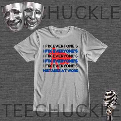 A gray graphic t-shirt featuring the text 'I FIX EVERYONE'S IX EVERYONE'S I FIX EVERYONE'S I FIX EVERYONE'S MISTAKES AT WORK' in black and blue, with a red 'X' crossing out the repeated phrase. The shirt is displayed on a dark gray textured background with silver comedy masks in the top-left corner and a vintage microphone in the bottom-right corner.