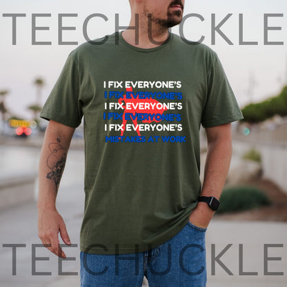 A green graphic t-shirt, featuring a text design that reads 'I FIX EVERYONE'S MISTAKES AT WORK' with a red scribble over repeated 'I FIX EVERYONE'S' lines. 
