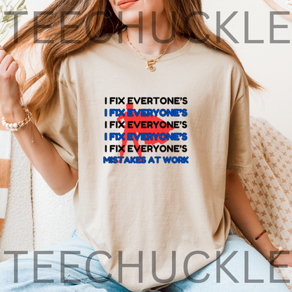 A woman wearing a sand graphic t-shirt with the slogan 'I FIX EVERYONE'S MISTAKES AT WORK' repeated in black and blue, crossed out in red. 