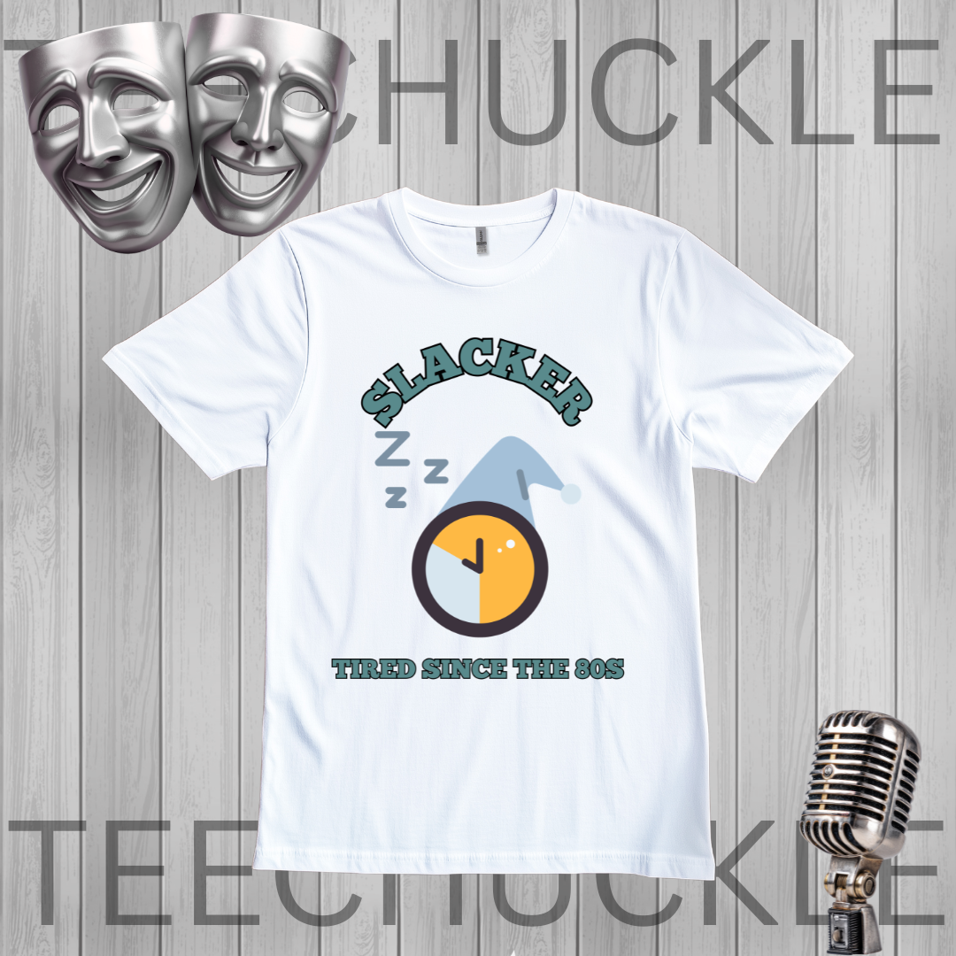 A white short-sleeve graphic t-shirt displayed on a gray wood-plank background, featuring a 90s-themed design with the word 'SLACKER', 'Z Z Z' sleep marks, a clock graphic, and 'TIRED SINCE THE 90S'. The image includes decorative props like silver theater masks and a vintage microphone