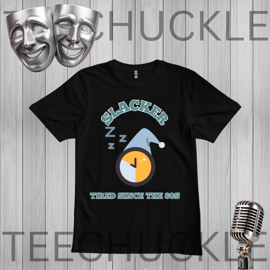 A black graphic t-shirt featuring a 'Slacker' theme with a sleeping clock and 'THIRD SINCE THE 80S' text, displayed on a gray wood plank background with a vintage microphone and silver comedy masks.