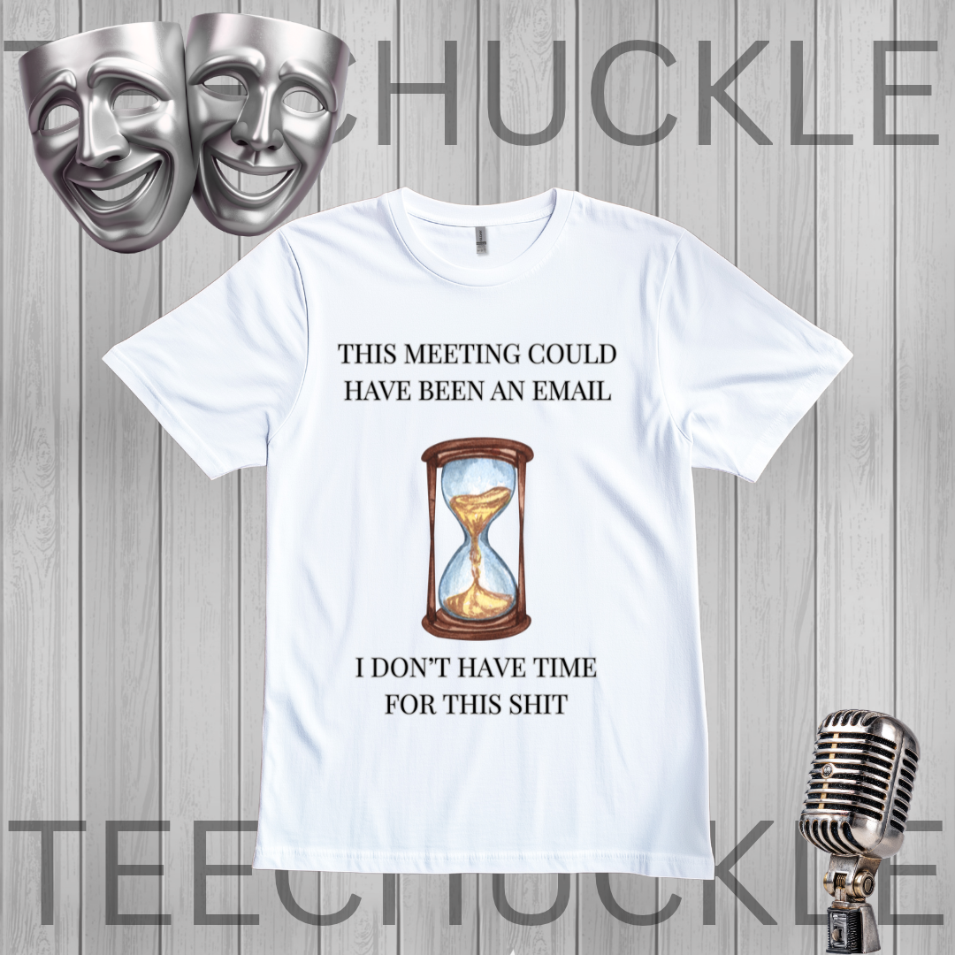 A white graphic t-shirt displayed on a gray wood-plank background, featuring a humorous meeting procrastination quote and an hourglass illustration. The image includes decorative props like silver theater masks and a vintage microphone