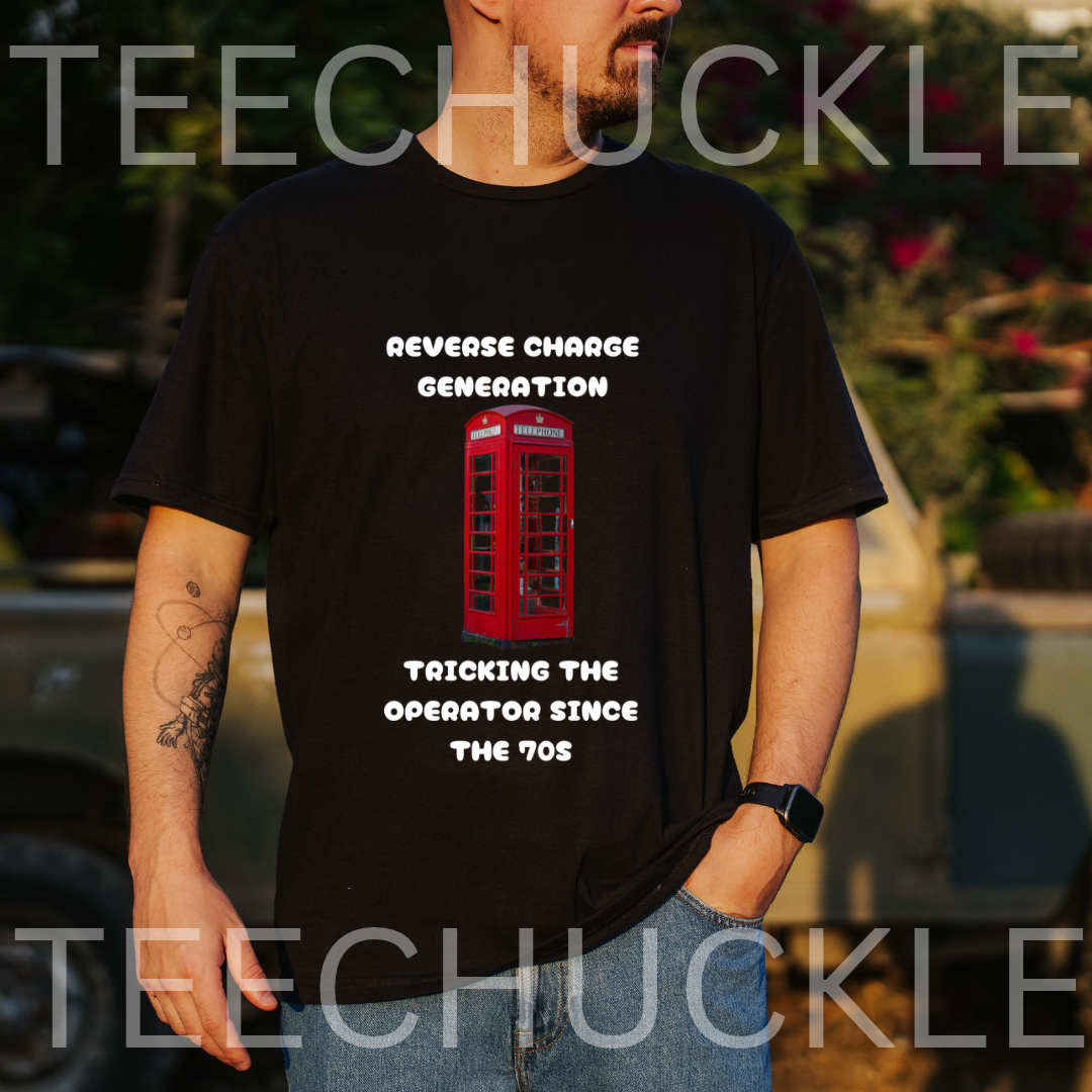 A man wearing a black graphic t-shirt with a red telephone booth and white text that reads 'REVERSE CHARGE GENERATION' and 'TRACKING THE OPERATOR SINCE THE 90S'. The background is an outdoor blurred setting 