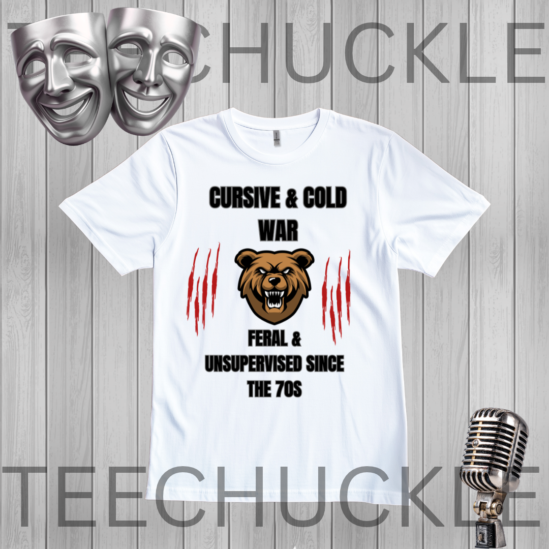 A white graphic t-shirt displayed on a gray wood plank background, featuring a bear head illustration, red claw marks, and the text 'CURSIVE & COLD WAR FERAL & UNSUPERVISED SINCE THE 70S'. The image includes decorative silver theater masks in the top left and a vintage microphone in the bottom right