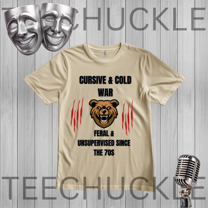 A sand graphic t-shirt featuring a brown bear illustration and the text 'CURSIVE & COLD WAR FERAL & UNSUPERVISED SINCE THE 70S' with red claw marks, displayed on a gray wood plank background with a microphone and theater masks.