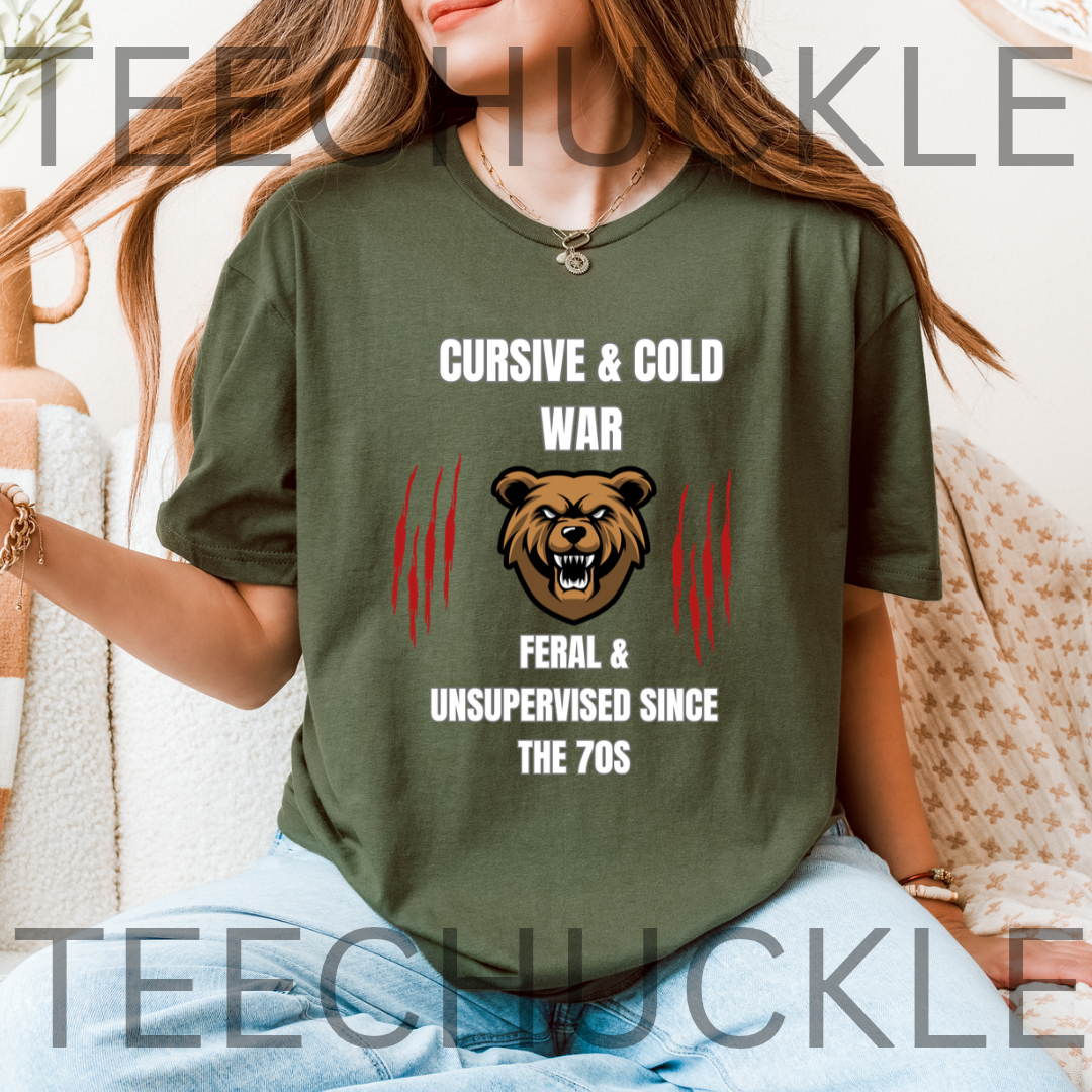 A woman wearing a green graphic t-shirt with a bear head design and the text 'CURSIVE & COLD WAR FERAL & UNSUPERVISED SINCE THE 70S'.
