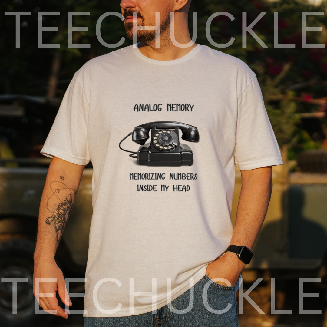 A man wearing a white graphic t-shirt with a black retro rotary phone design and the text 'ANALOGIC MEMORY' and 'MEMORIZING NUMBERS INSIDE MY HEAD'. 