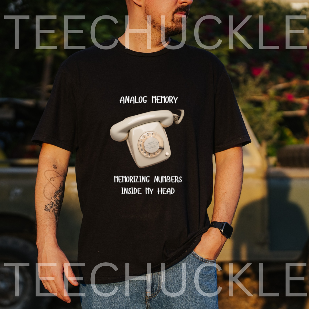 A man wearing a black graphic t-shirt with a white retro rotary phone design and the text 'ANALOGIC MEMORY MEMORIZZING NUMBERS INSIDE MY HEAD'.