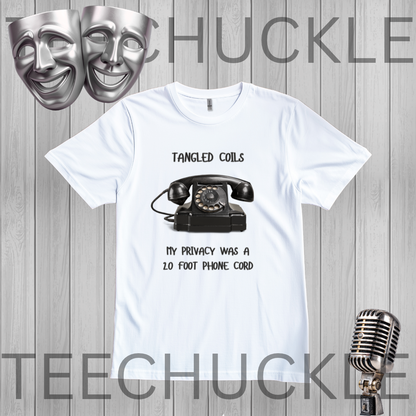 A white short-sleeve graphic T-shirt laid flat on a gray wood-plank background. The shirt has a black printed design featuring a vintage rotary telephone and the text 'TANGLED COILS' above it and 'MY PRIVACY WAS A 20 FOOT PHONE CORD' below it.