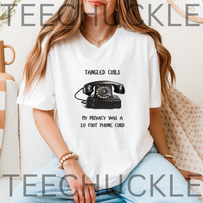 A woman wearing a white graphic t-shirt with a black retro rotary phone and the text 'TANGLED COILS MY PRIVACY WAS A 20 FOOT PHONE CORD'. 
