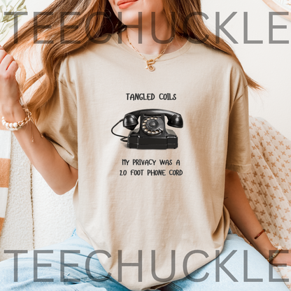 A woman wearing a sand graphic t-shirt with a black rotary phone print and the text 'Tangled Coils My Privacy Was A 2 Foot Phone Cord'.