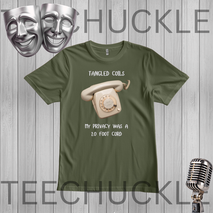 A green graphic t-shirt featuring a vintage cream rotary phone and the text 'Tangled Coils' and 'My Privacy Was A 20 Foot Cord'. The t-shirt is displayed on a gray wood-plank background with a silver comedy mask, and a vintage microphone.