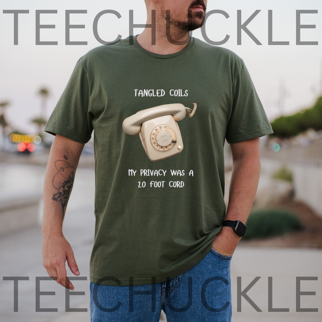 A green short-sleeve graphic T-shirt. The shirt has a black printed design featuring a vintage rotary telephone and the text 'TANGLED COILS' above it and 'MY PRIVACY WAS A 20 FOOT PHONE CORD' below it.