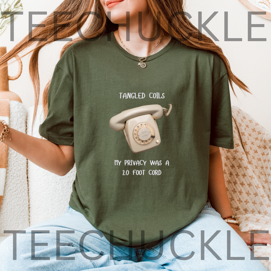A woman wearing a green graphic t-shirt with a retro rotary phone design and the text 'Tangled Coils My Privacy Was a 20 Foot Cord'. 