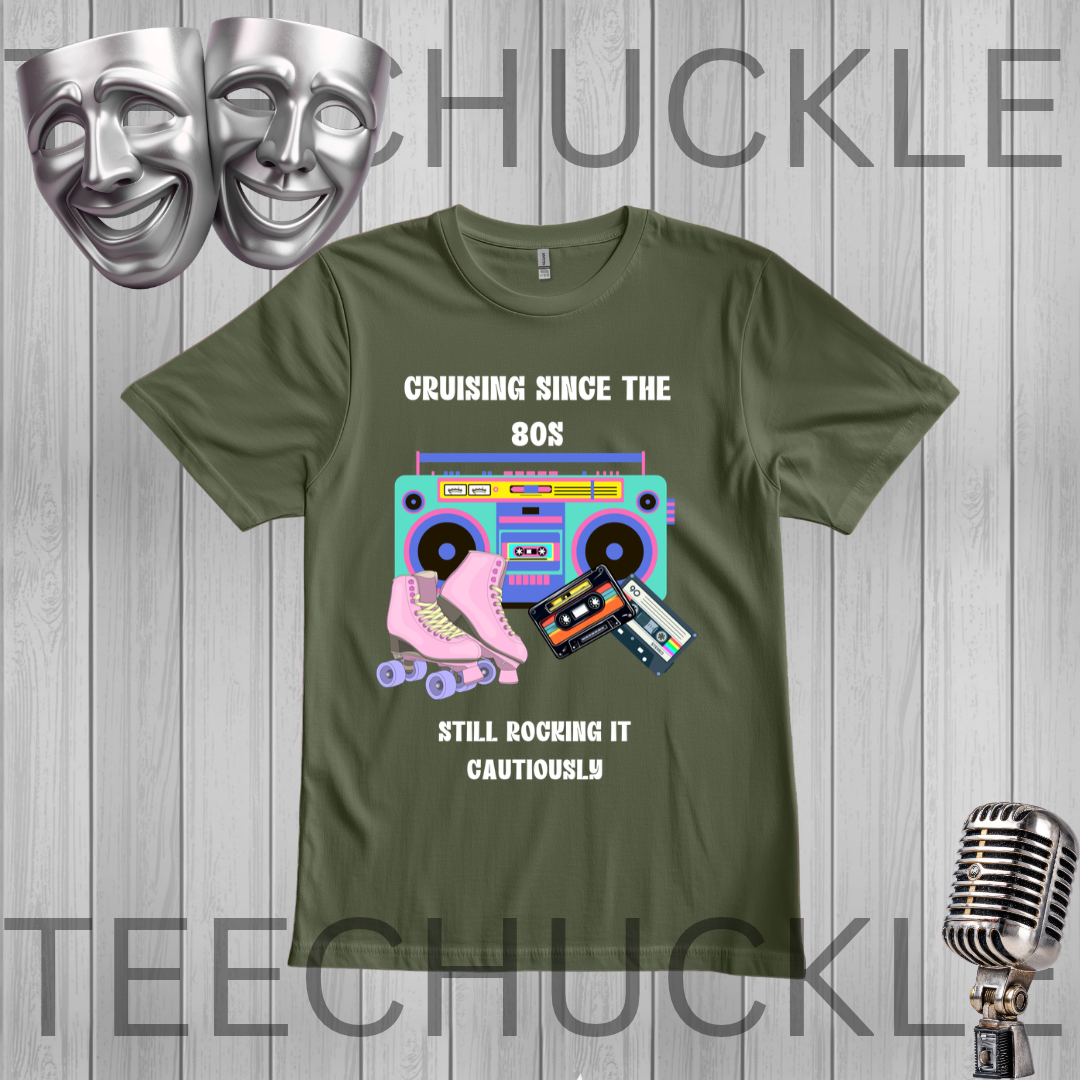A green graphic t-shirt featuring retro 80s-themed illustrations (boombox, pink roller skate, cassette tape) with the text 'CRUISING SINCE THE 80S STILL ROCKING IT CAUTIONOUSLY'. The t-shirt is displayed on a gray wood-plank background with decorative silver theater masks, a vintage microphone