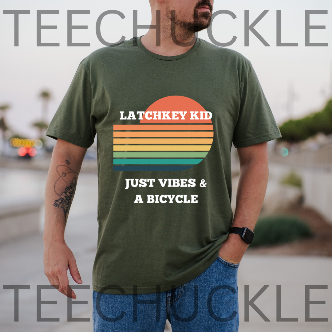 A man wearing a green graphic t-shirt with a retro sunset design and the text 'LATCHKEY KID JUST VIBES & A BICYCLE'. 