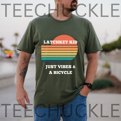 A man wearing a green graphic t-shirt with a retro sunset design and the text 'LATCHKEY KID JUST VIBES & A BICYCLE'. 