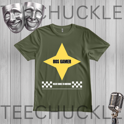 A green graphic t-shirt displayed on a gray wood plank background. The shirt features a yellow star graphic with the text '80S GAMER' in black, and a white 'INSERT COIN TO CONTINUE' checkered banner at the bottom.
