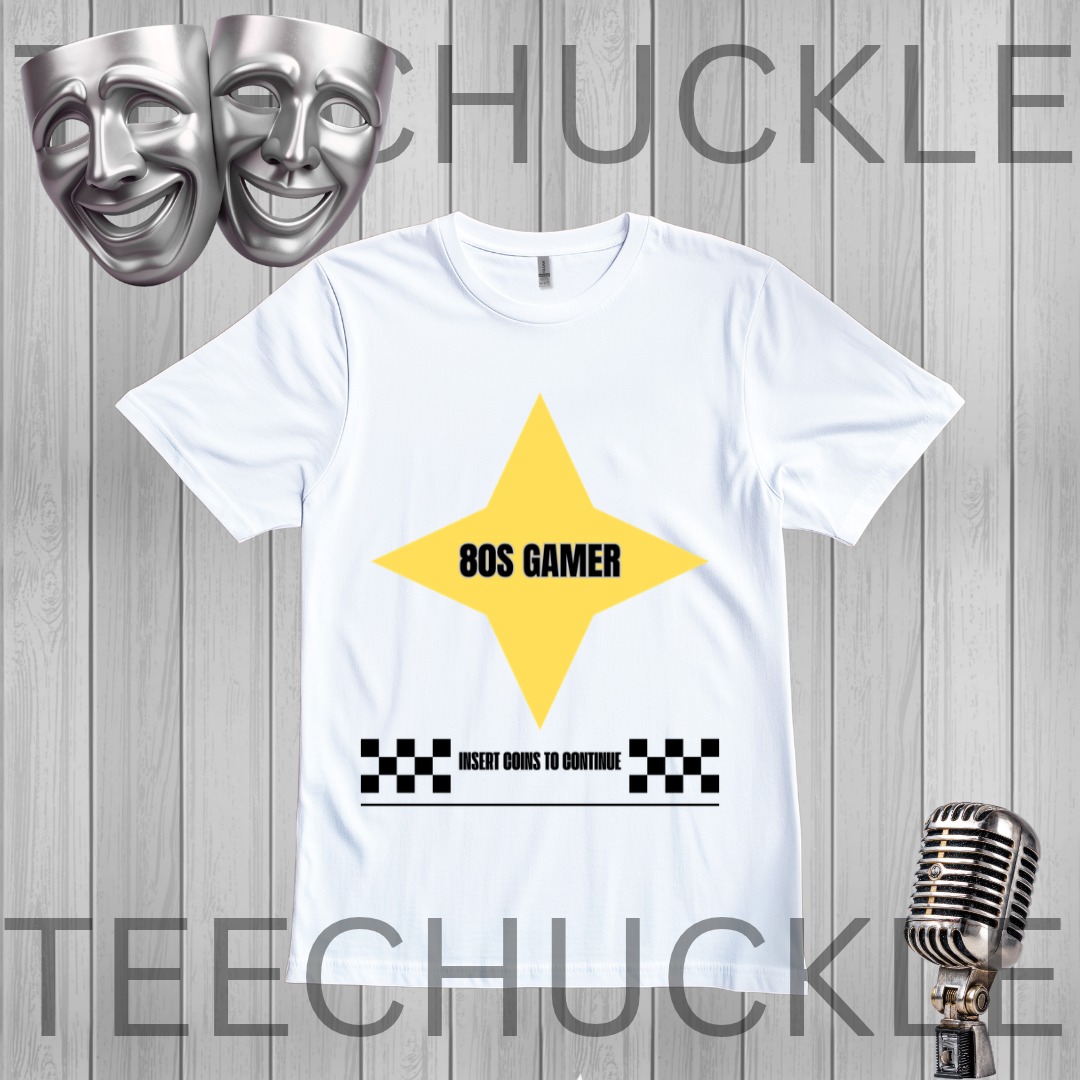 A white short-sleeve t-shirt with a yellow star graphic and '80S GAMER' text, displayed on a gray wood-plank background with theatrical masks, a vintage microphone