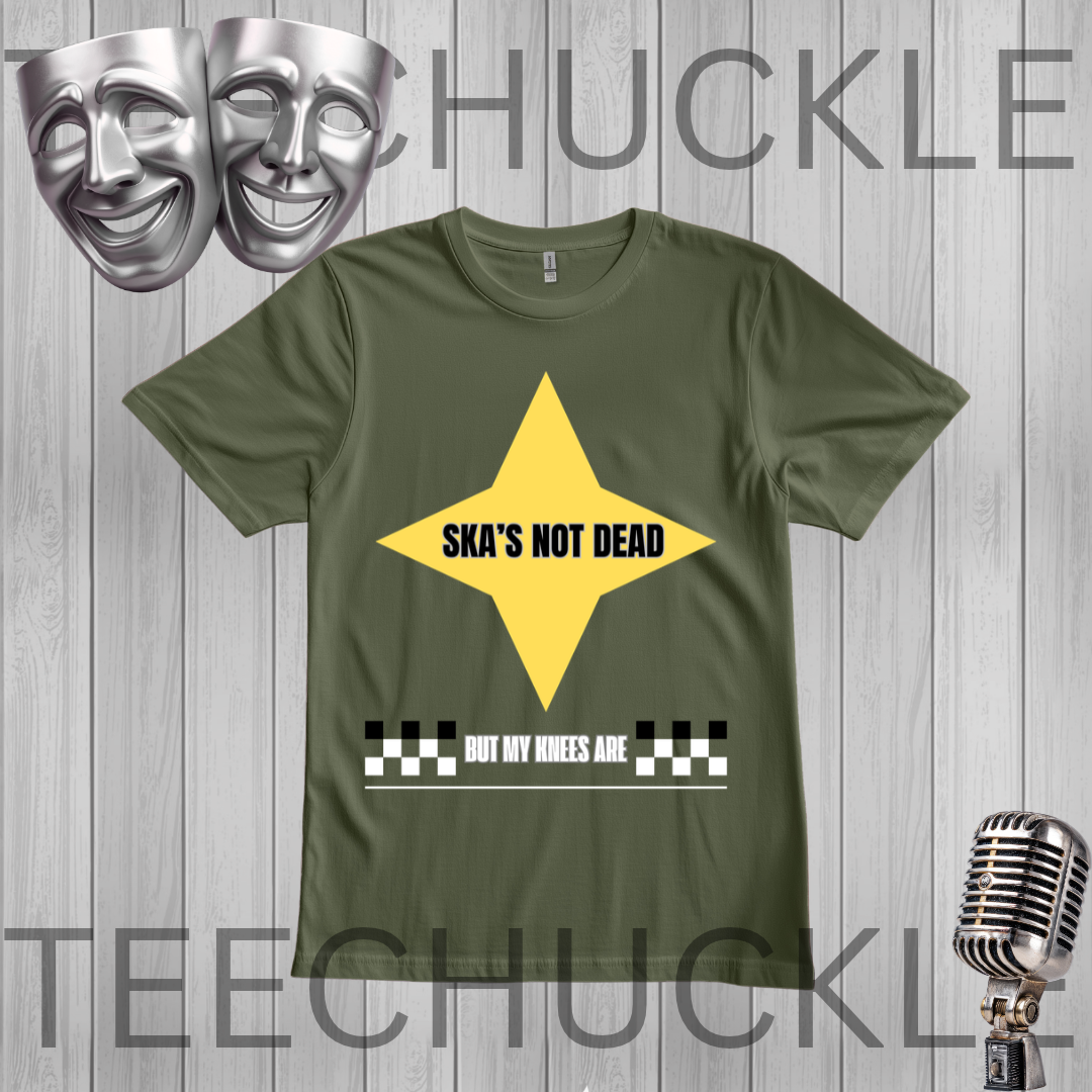 A green graphic t-shirt displayed on a gray wood-plank background. The shirt features a yellow diamond graphic with the text 'SKA'S NOT DEAD' in black, and a white text banner below reading 'BUT MY KNEES ARE' with a black and white checkered bar.