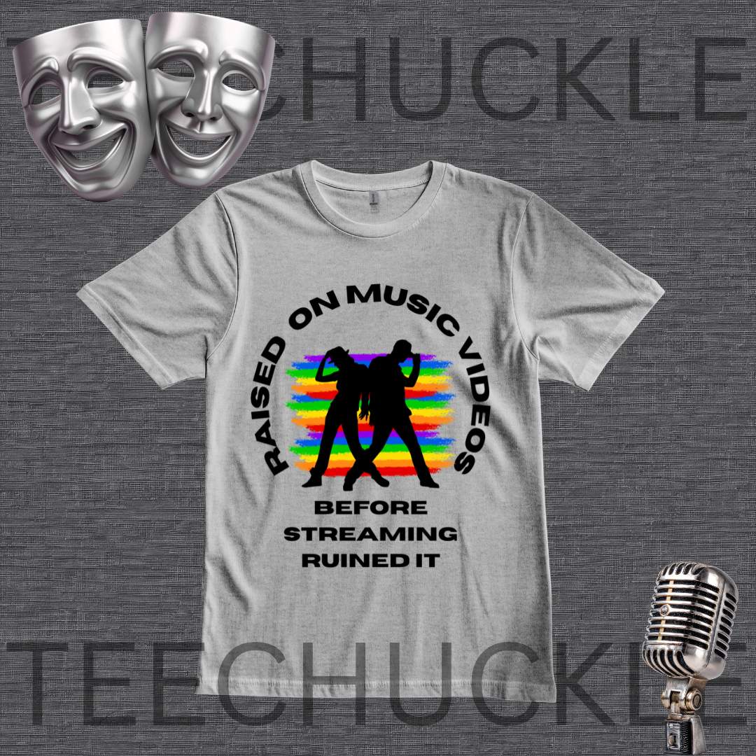 A gray graphic t-shirt displayed on a dark gray textured background. The shirt features a black circular graphic with the text 'RAISED ON MUSIC VIDEOS BEFORE STREAMING RUINED IT' surrounding a black silhouette of a person in front of a colorful rainbow-striped background.