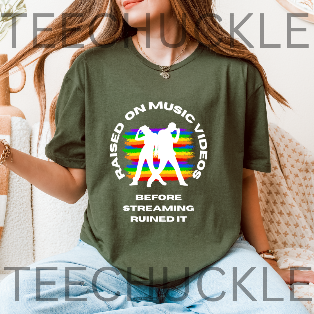 A woman wearing a green graphic t-shirt with a white and rainbow design that reads 'RAISED ON MUSIC VIDEOS BEFORE STREAMING RUINED IT'. 