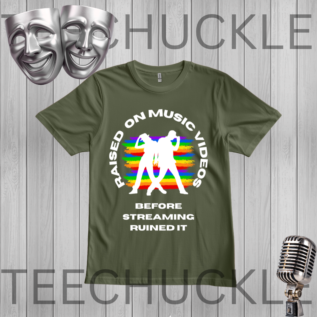 A green graphic t-shirt displayed on a gray wood-plank background. The shirt features a white circular text graphic reading 'RAISED ON MUSIC VIDEOS BEFORE STREAMING RUINED IT' surrounding a white silhouette of a person dancing in front of a retro rainbow-striped background.