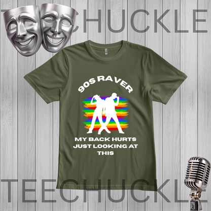 A green graphic t-shirt displayed on a gray wood plank background. The shirt features a white graphic of two silhouettes dancing in front of a retro rainbow-striped microphone stand, with the text '90S RAVER MY BACK HURTS JUST LOOKING AT THIS'.