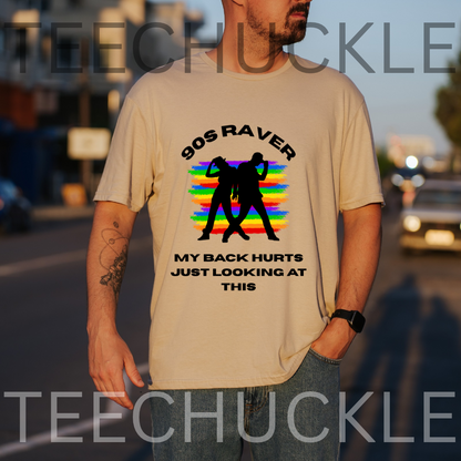 A man wearing a beige graphic t-shirt with a '90s Raver' design featuring a rainbow stripe background and black silhouette figures, with text reading 'MY BACK HURTS JUST LOOKING AT THIS'.