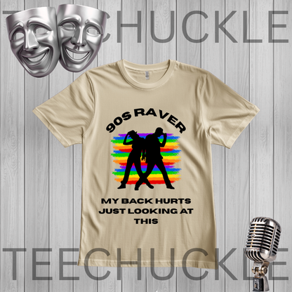 A sand graphic t-shirt displayed on a gray wood-plank background. The shirt features a black graphic of two silhouettes dancing in front of a rainbow-striped background, with the text '90S RAVER' above and 'MY BACK HURTS JUST LOOKING AT THIS' below.