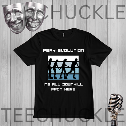 A black graphic t-shirt displayed on a gray wood plank background, featuring the text 'PEAK EVOLUTION' and 'ITS ALL DOWNHILL FROM HERE' with roller derby silhouettes. Silver theater masks and a vintage microphone are floating as decorative props