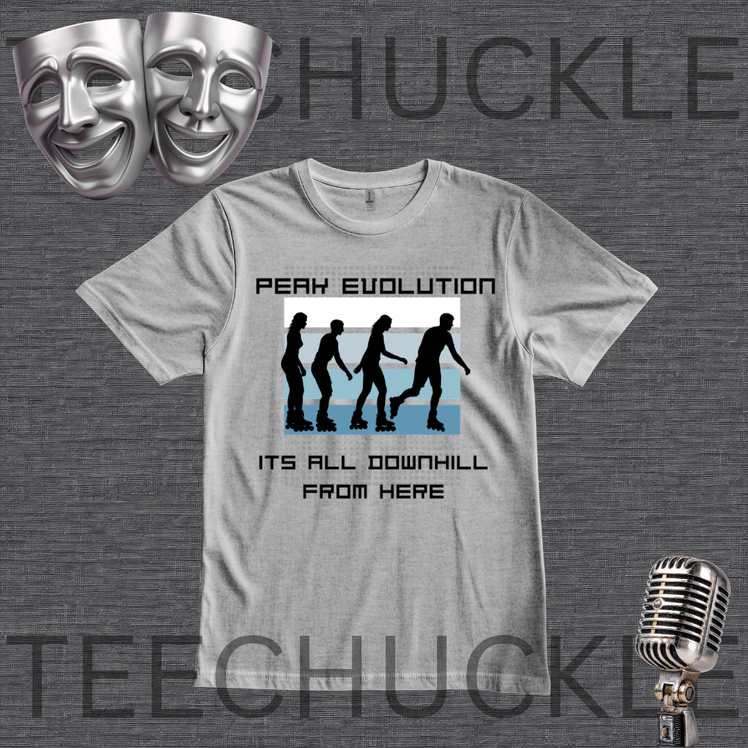 A gray graphic t-shirt displayed on a dark gray textured background, featuring a 'Peak Evolution' downhill silhouette graphic. The image includes decorative props like silver theater masks in the top-left and a vintage microphone in the bottom-right