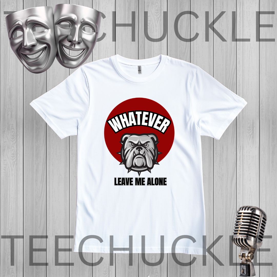 A white short-sleeve graphic t-shirt displayed on a gray wood plank background, featuring a red circular graphic with a bulldog and the text 'WHATEVER LEAVE ME ALONE'. The image includes decorative props like silver theater masks and a vintage microphone
