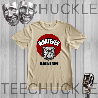 A graphic t-shirt featuring a red circle with a bulldog illustration and the text 'WHATEVER LEAVE ME ALONE'. The t-shirt is displayed on a gray wood plank background with a silver microphone and two silver comedy masks,