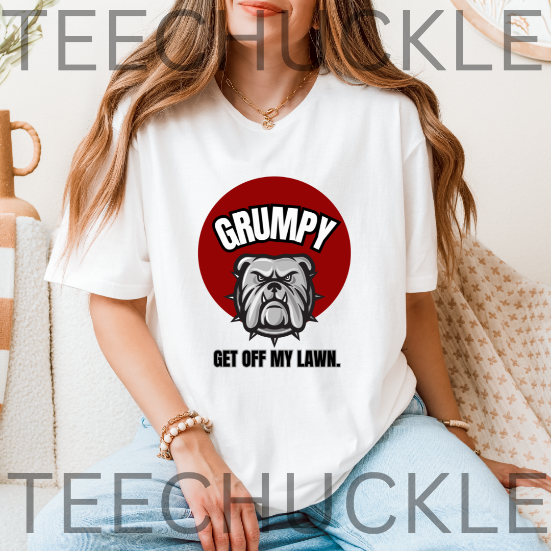 A woman wearing a white graphic t-shirt with a red circular design featuring a bulldog and the text 'GRUMPY GET OFF MY LAWN.'