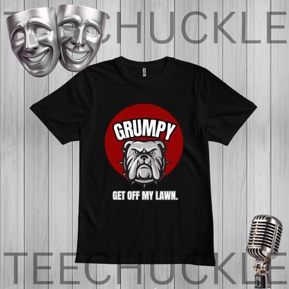 A black short-sleeve graphic t-shirt displayed on a gray wood-plank background. The shirt features a red circular graphic with a bulldog illustration and the text 'GRUMPY GET OFF MY LAWN.
