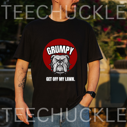 A man wearing a black graphic t-shirt with a red circular bulldog design and the text 'GRUMPY GET OFF MY LAWN.' The background is an outdoor setting with a blurred vehicle and foliage