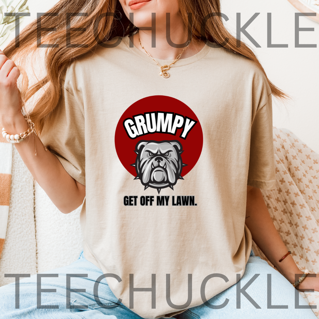 A woman wearing a sand graphic t-shirt with a red circular bulldog design and the text 'GRUMPY GET OFF MY LAWN.' 