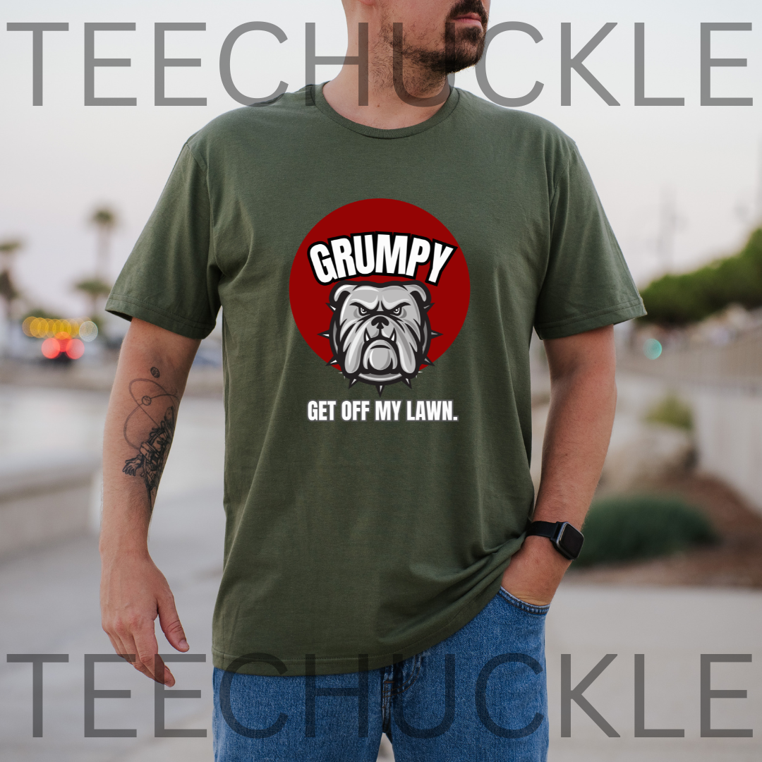 A man wearing a green graphic t-shirt with a red circular bulldog design and the text 'GRUMPY GET OFF MY LAWN.' The background is a blurred outdoor street scene,