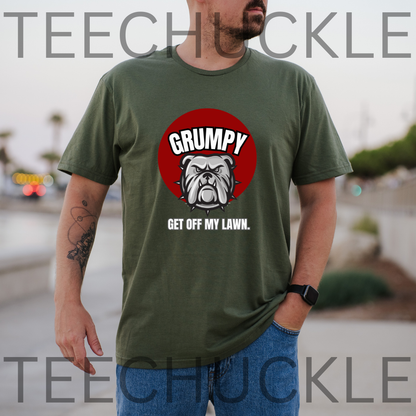 A man wearing a green graphic t-shirt with a red circular bulldog design and the text 'GRUMPY GET OFF MY LAWN.' The background is a blurred outdoor street scene,