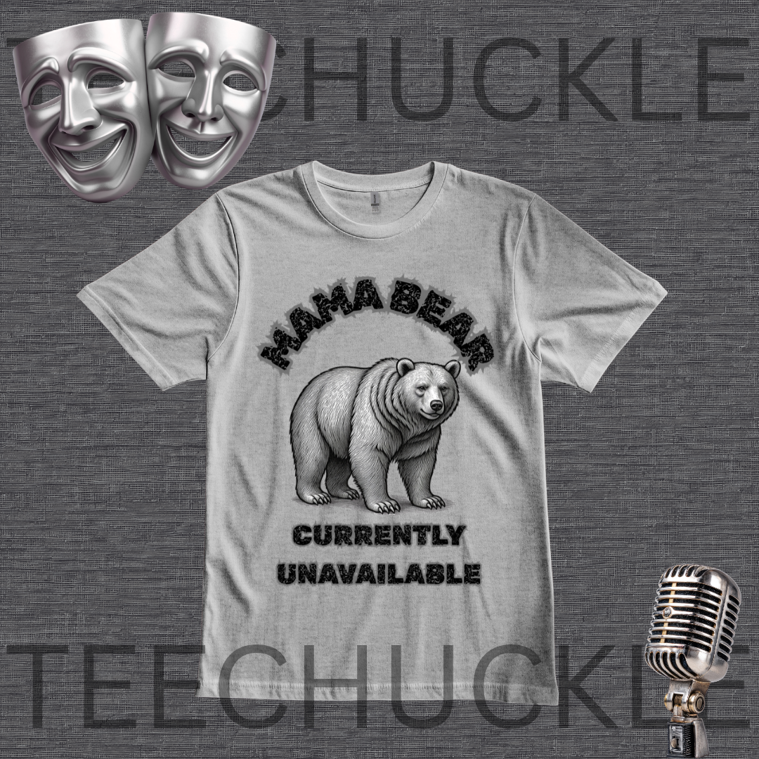 A gray graphic t-shirt featuring a black and white illustration of a bear with the text 'MAMA BEAR' above and 'CURRENTLY UNAVAILABLE' below. The t-shirt is displayed on a dark gray textured background with decorative props including two silver theater masks, a vintage microphone