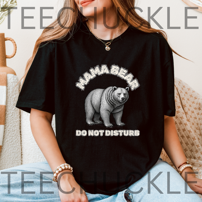 A woman wearing a black graphic t-shirt with a white 'MAMA BEAR DO NOT DISTURB' design featuring a bear illustration. 