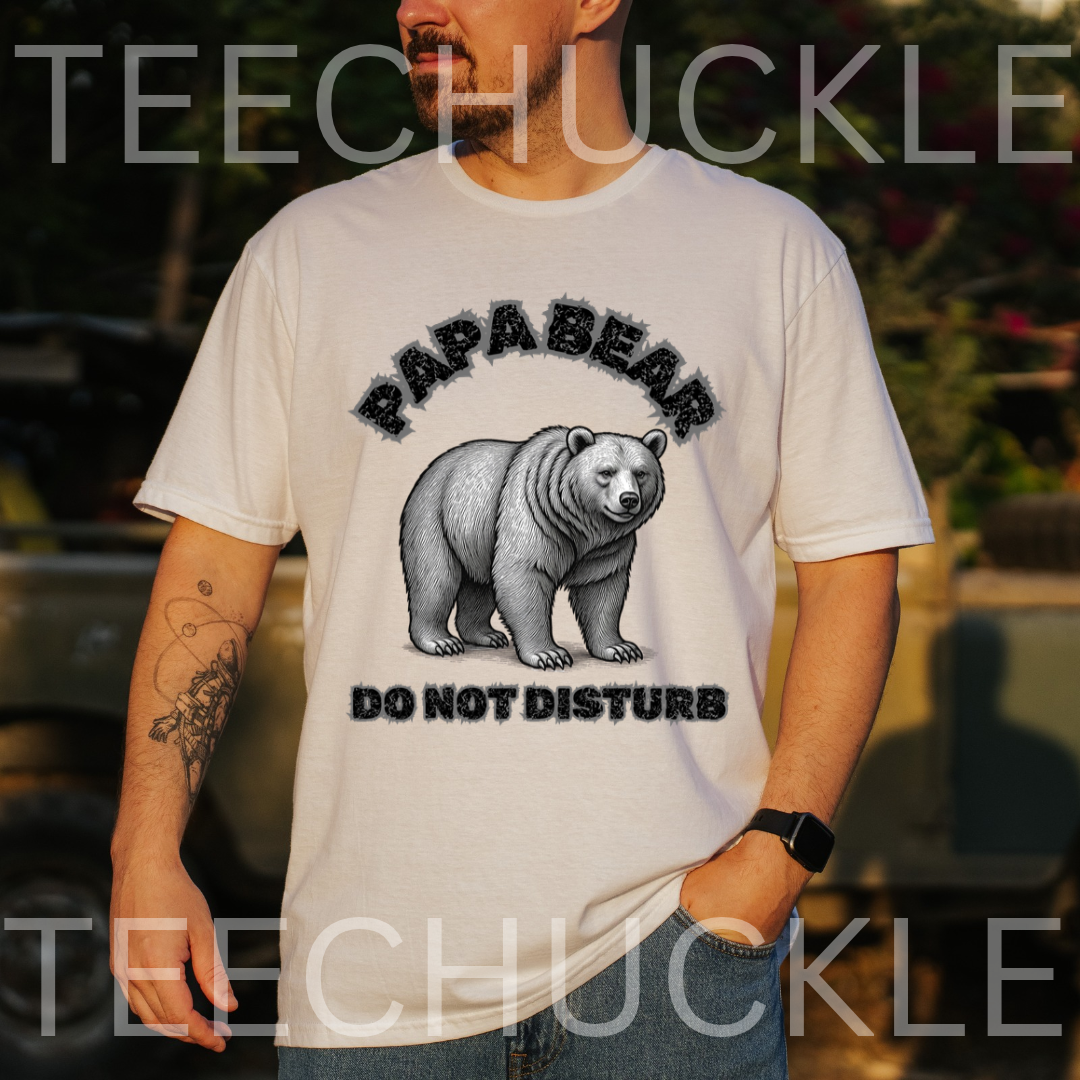 A man wearing a white graphic t-shirt with a black and gray print of a bear and the text 'PAPABEAR DO NOT DISTURB'. 