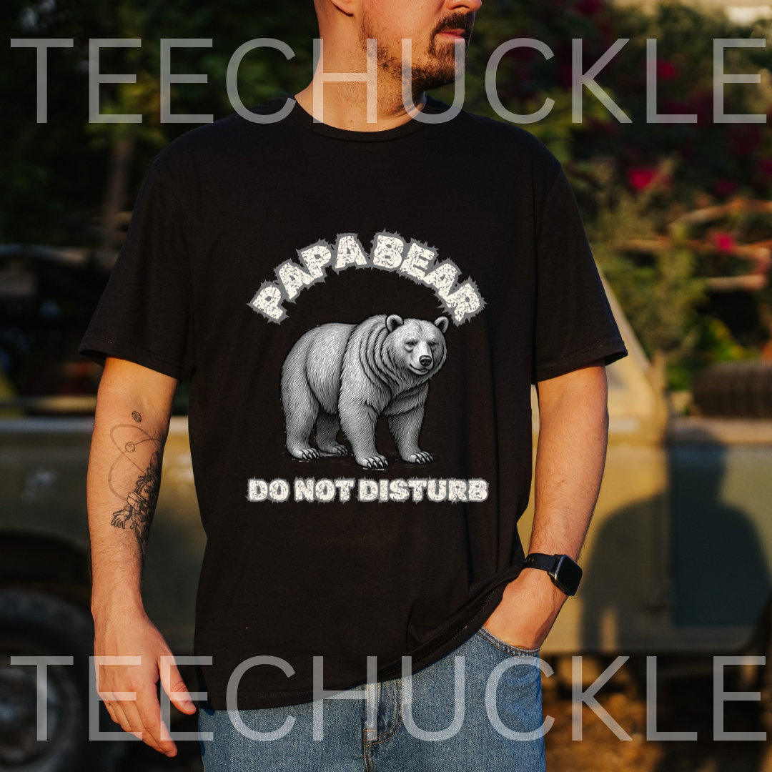 A man wearing a black graphic t-shirt with a white polar bear and the text 'PAPABEAR DO NOT DISTURB'. The background is an outdoor setting with a blurred vehicle and foliage